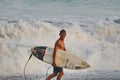 A surfer walks along the shore with his surfboard at Jaco Beach