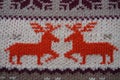 Jacquard knitted pattern. Geometric ornament for Christmas or New Year. Two red deer on a white knitted background