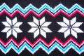 Jacquard knitted pattern. Geometric ornament for Christmas or New Year. Knitted white snowflake, blue pink zigzag on a