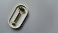 Jade roller for face massage or gua sha on a concrete tray. Blue paper background. Top view.