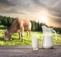 Jag and glass of milk against background of cow and mountain pas Royalty Free Stock Photo