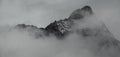 Jagged mountain peaks covered in snow and hidden in mist and fog