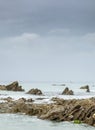 Jagged rock pinnacles juxtaposed with distant sailing boat,Dollar Cove,Gunwalloe, Helston,South Cornwall,England,UK Royalty Free Stock Photo