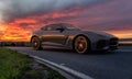 Jaguar F-Type cornering on the road into a spectacular sunset