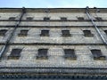 Jail. Antique prison wall with barred windows and barbed wire