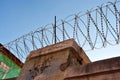 Jail fence top with barbed wire, winter bright sky background