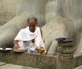 Hassan, Karnataka, India - September 12, 2009 Jain priest near ancient, granite monolithic statue of Lord Gommateshwara