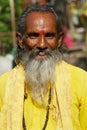 Portrait of a senior hindu monk wearing traditional yellow dress at the street in Jaipur, India.