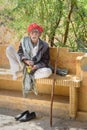 Elderly Indian man with grey moustache wears red Rajasthani turban or pagari on the bench in Jaisalmer. Rajasthan. India Royalty Free Stock Photo