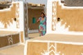 Woman with her traditional clothing  stands on the entrance of her traditionally painted house in Thar desert, Khuri, Jaisalmer Royalty Free Stock Photo