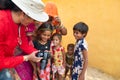 Female traveller and woman photographer showing pictures of smiling and happy Rajasthani women and children to themselves, in a