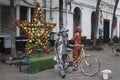 The statue of a human being in a tourist park in Asia is silver and gold in color with a flower star decoration