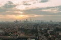 Jakarta Cityscape with high rise, skyscrapers and red tile hip roof local buildings with fog and evening sky in background