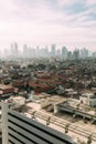 Jakarta Cityscape with high rise, skyscrapers and red tile hip roof local buildings with fog in the morning