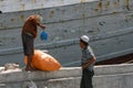 port workers weighing a sack in front of an old vessel