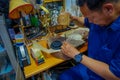 JAKARTA, INDONESIA - 3 MARCH, 2017: Local handcraft worker sitting by workplace desk using his tools creating