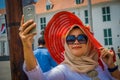 JAKARTA, INDONESIA - 3 MARCH, 2017: Local woman wearing large red hat takes a selfie while posing with sunglasses