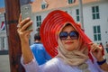 JAKARTA, INDONESIA - 3 MARCH, 2017: Local woman wearing large red hat takes a selfie while posing with sunglasses