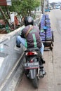 Behind the man sitting on the motorcycles beside the road who is a Grab bike in Indonesia