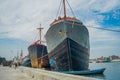 JAKARTA, INDONESIA - MAY 06, 2017: Huge boat in old port area of Jakarta, fishing boats, fishermen, cranes and trucks