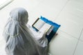 Unknown woman reads Quran with a pointer stick Royalty Free Stock Photo