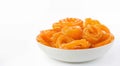 A jalebi in a bowl against a white backdrop, holi photo