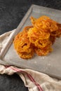 Jalebi Indian sweets on a metal tray on a dark background.