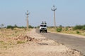 People drive four wheel car by an asphalt countryside road at the Great Thar desert near Jamba, India. Royalty Free Stock Photo