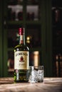 Jameson whiskey bottle and glass with ice cubes on wooden table