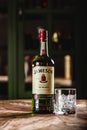 Jameson whiskey bottle and glass with ice cubes on wooden table