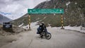 Jammu and Kashmir, India - June 16 2019: A biker poses for a photograph below the sign board of & x22;Welcome to ladakh