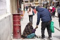 Tibetan people giving money to old indian old woman beggar or untouchables caste sit and begging in market at Leh Ladakh on March