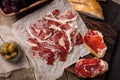 Jamon Iberico with white bread, olives on toothpicks and fruit on a wooden background. Top view Royalty Free Stock Photo