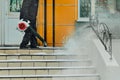 A janitor cleans snow from the stairs next to the shop with a wind blower. Lumps of snow and snowflakes in the air. Work Royalty Free Stock Photo