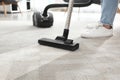 Janitor hoovering carpet with vacuum cleaner indoors