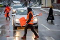 Janitor lady wearing orange vest walks with snow shovel