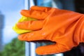 A janitor in an orange glove washes the window with a yellow cloth, polishes the glass close-up Royalty Free Stock Photo