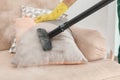 Janitor removing dirt from sofa cushion with steam cleaner