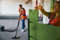 Janitor vacuuming the carpet in the presence of her colleagues Royalty Free Stock Photo