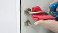Janitor wear surgical gloves cleaning the door handles with an antiseptic alcohol sanitizer during a viral epidemic corona virus