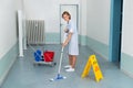Janitor With Wet Caution Sign And Cleaning Equipments Royalty Free Stock Photo