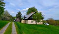 Mountain cottage with a tree in front of it, grass around it, and access road next to it