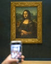 Hand phone capturing Mona Lisa (Lisa del Giocondo) portrait by the Italian artist Leonardo da Vinci, Paris, France 2024