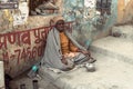 An old Indian beggar waits for alms on a street