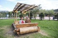Couple sitting in a car made of wooden logs, flintmobile. Sopo Bridge Park