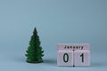 January 1st. Date on wooden cube calendar and Christmas tree on blue pastel background. New year concept Royalty Free Stock Photo