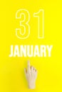 January 31st . Day 31 of month, Calendar date.Hand finger pointing at a calendar date on yellow background.Winter month, day of
