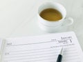 January 1st diary, a pen and a cup of tea on a white marble texture background. Royalty Free Stock Photo