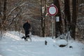 January 13-th, Bulgaria: A man with red hat and his dog are running in snow winter forest. Street sign on the corner.