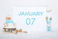 January 7th. Teddy bear sitting on a sled, blue skis and a calendar date on white snow. Day 7 of month. Royalty Free Stock Photo